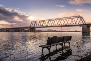 Bench in water with bridge in the background in Deventer. By Bart Ros on Unsplash